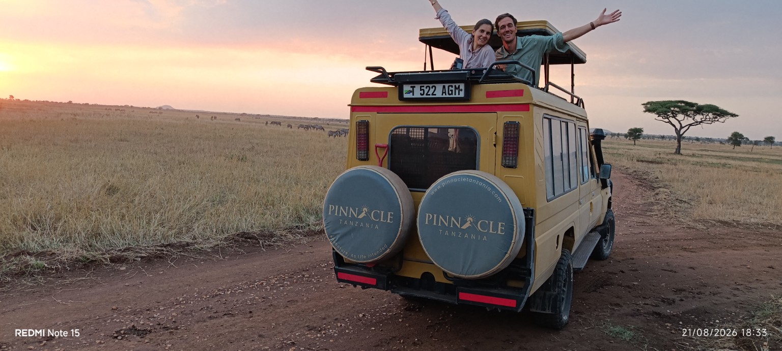 Honeymoon couple celebrating from a Pinnacle safari vehicle at sunset